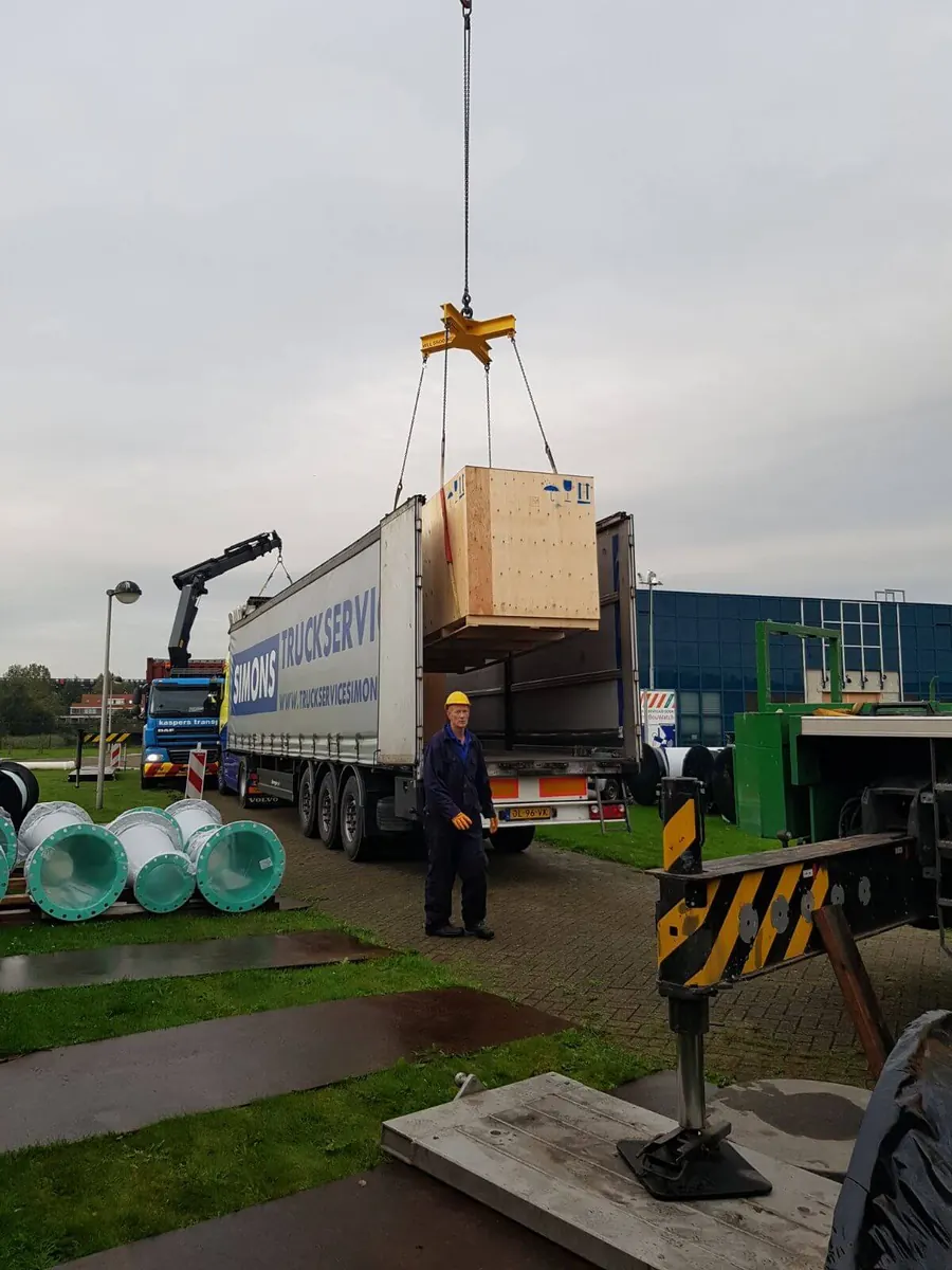 Een krat met pompdelen hangt aan de kraan boven de vrachtwagen
