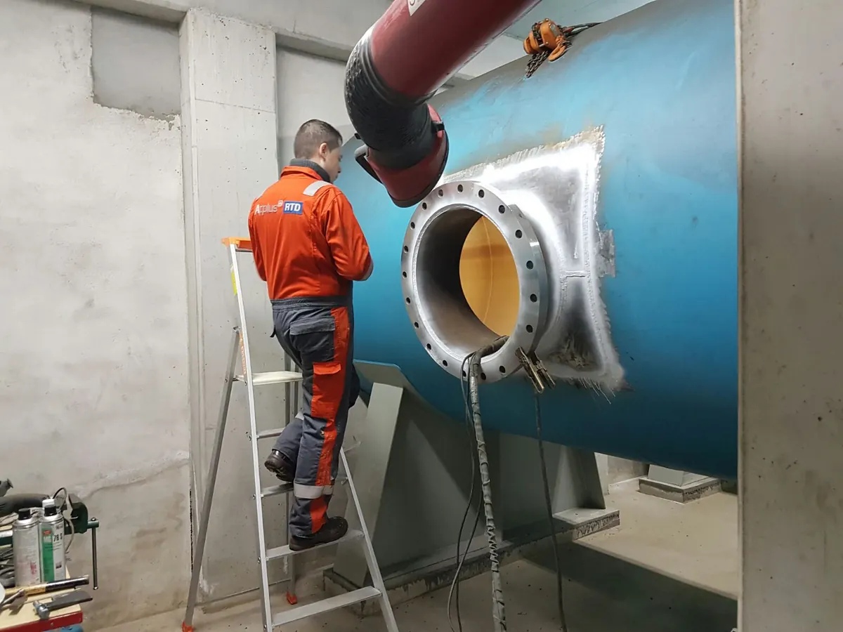 Monteur op een ladder bij het mangat van een blauwe hydrofoortank