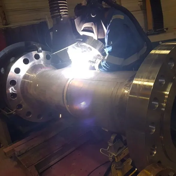 Lasser last een flens aan een stalen leiding, met de vonken van de lasboog